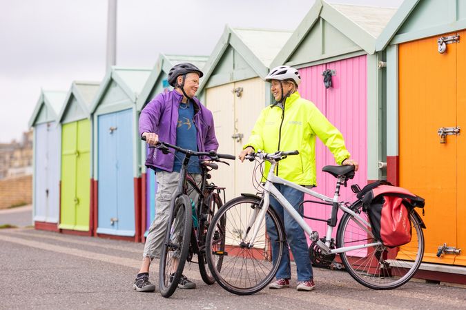 Two older people with bicycles standing in front of colorful sheds