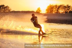 Man wakeboarding on a lake with sunset in the background 0vOLG5
