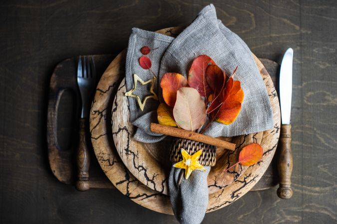 Autumnal table setting with yellow and red leaves on rustic background with copy space