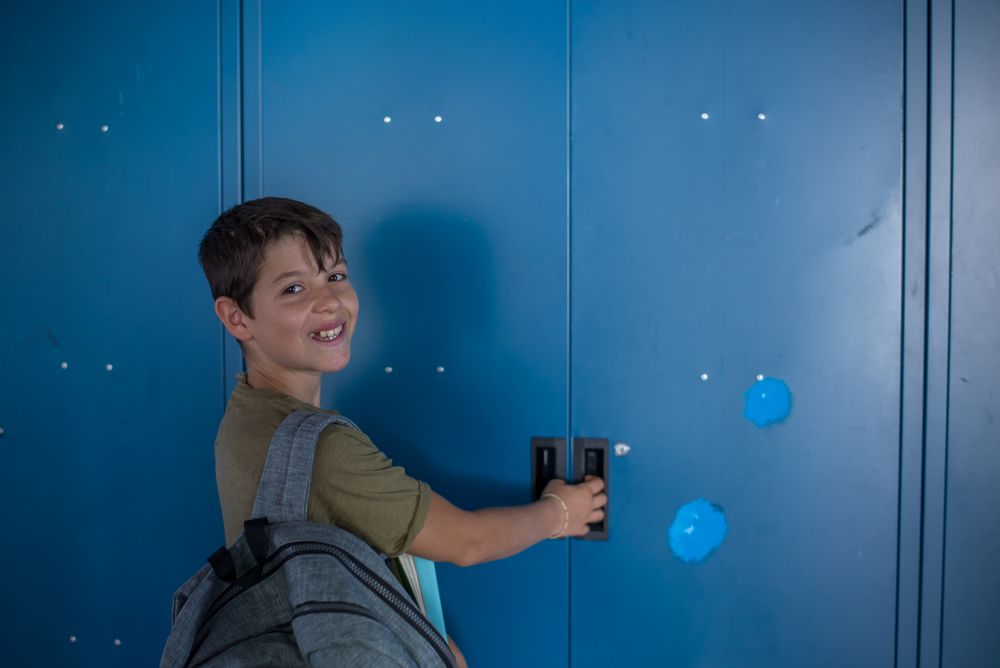 Teenager turning around smiling at his blue school locker