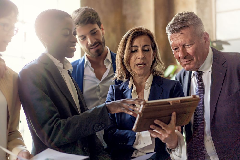 Multi-ethnic team in modern office looking at tablet screen