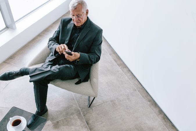 Top view of old businessman using with mobile phone in office lobby