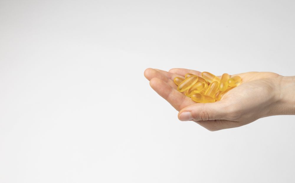 The hand of a woman holds a handful of oil capsules with omega 3, food supplement