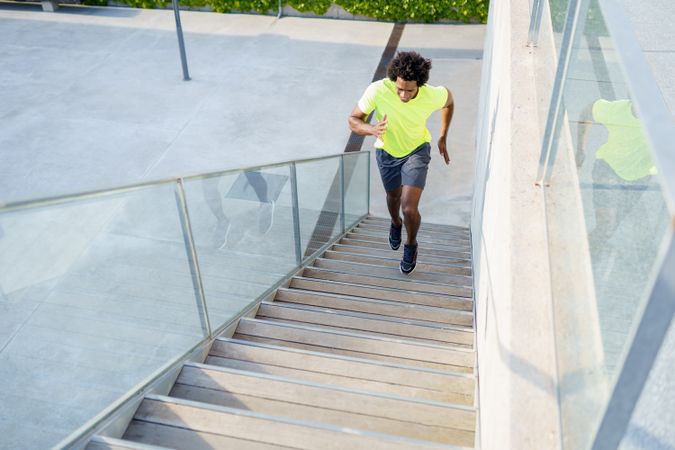 Fit man in neon T-shirt exercising on outdoor staircase