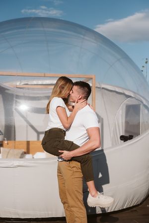 Affectionate couple kissing near bubble hotel