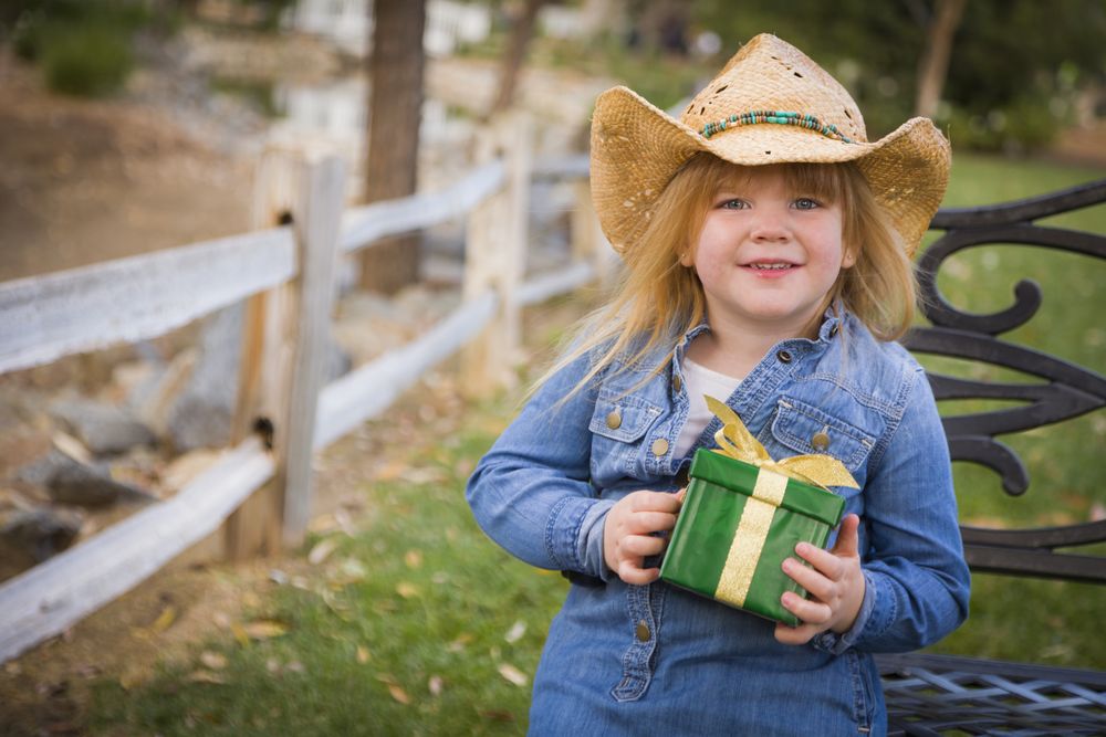 Young Girl Wearing Holiday Clothing Holding Christmas Gift Outside