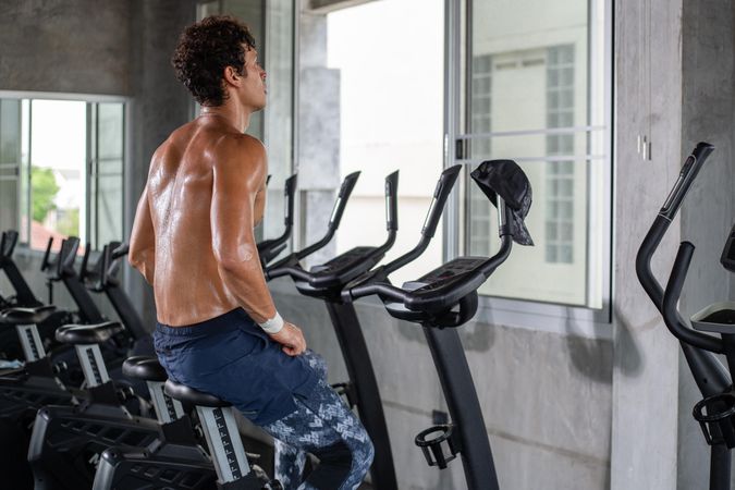 Muscular male working out on cycling machine