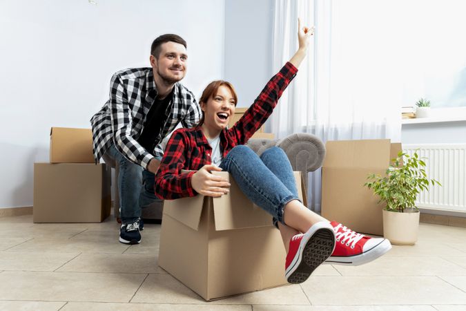 Moving concept, couple man and woman with boxes in apartment.