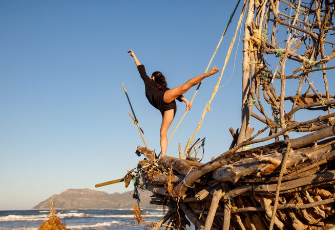 Young woman with upped leg on decorative wooden ship near water on shore