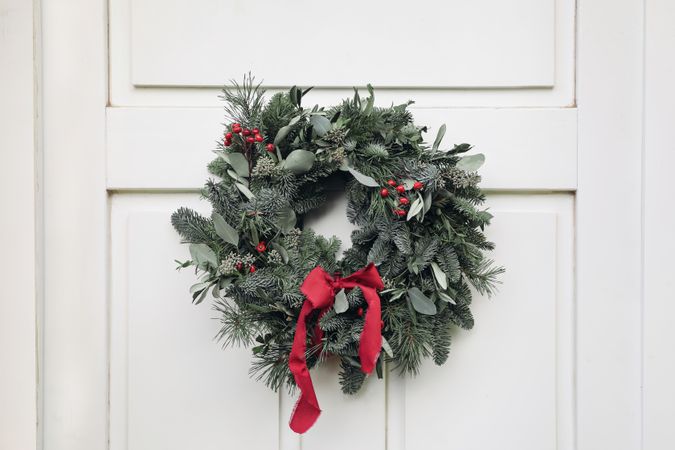 Christmas advent wreath, garland of fir, pine tree branches and red berries hung on door