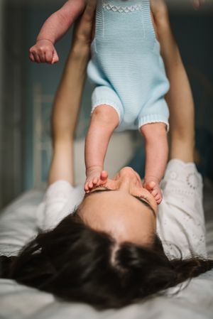 Mother playing with baby on bed
