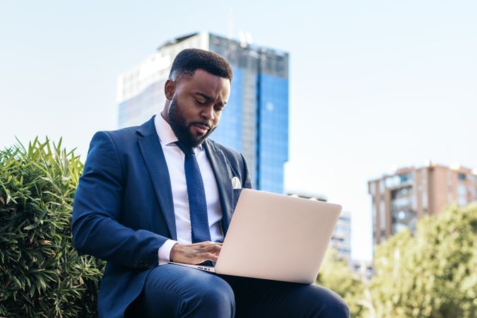 Business man in suit working with laptop outside