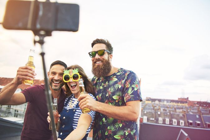 Group of friends with beer and selfie stick with fun pineapple sunglasses