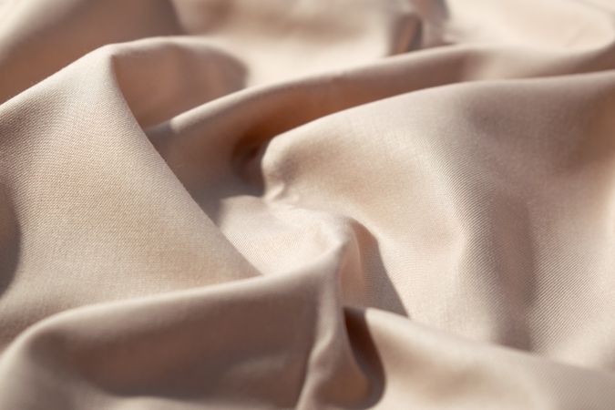 Close up silk shiny light brown fabric background texture.
