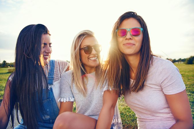 Happy multi-ethnic female friends sitting in sunny field