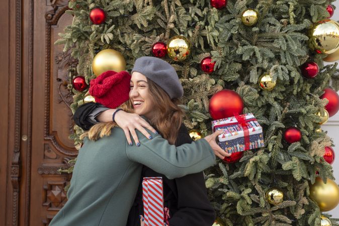 Happy young women in Christmas caps exchanging gifts