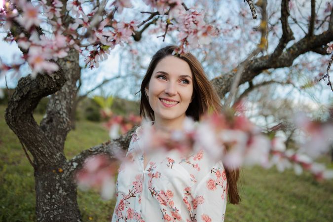 Young happy woman between trees in garden