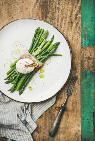 Asparagus and soft boiled egg on plate, on wooden table with green trim