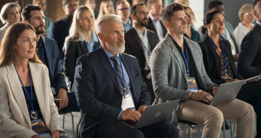 Mature White Man Sitting in a Crowded Audience at a Business Forum.