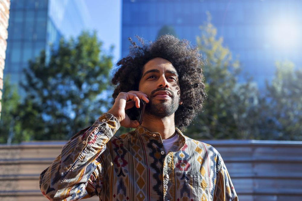 Man talking on a mobile phone while standing outdoors on a sunny day