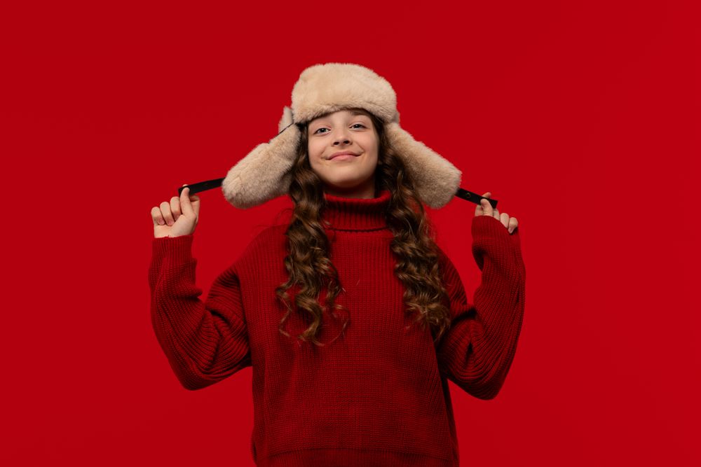 Happy girl in fur hat confidently holds ear flaps hat