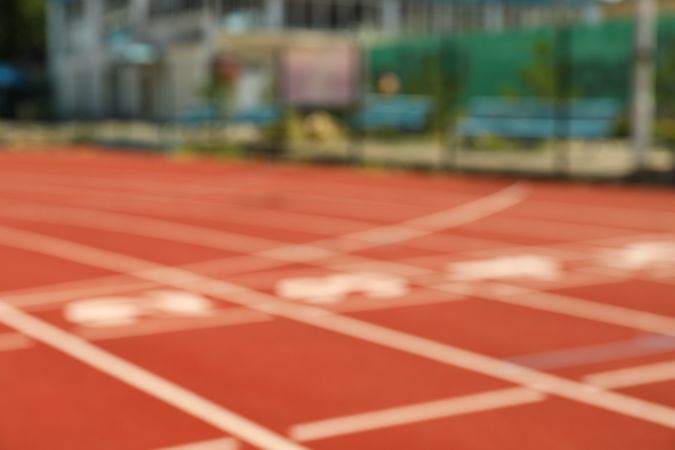 Start of red athletic track with numbers, blurred background