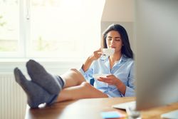 Arab woman sitting at her desk with feet up sipping tea