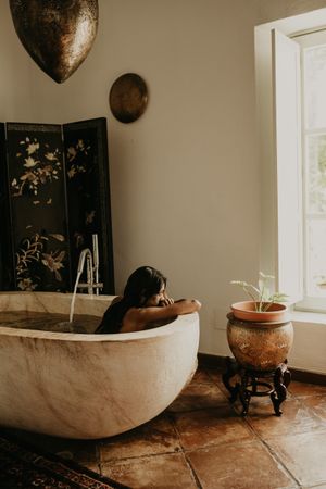 Melancholic Woman sitting and washing in bath