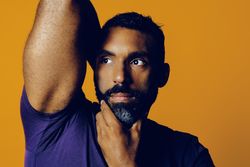 Sensual Black man in yellow studio with one hand to his chin