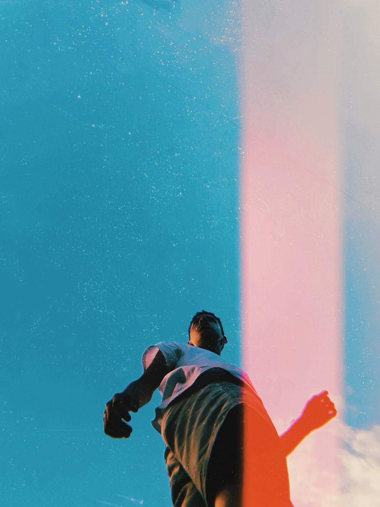 Low angle view of young man in light shirt standing under blue sky