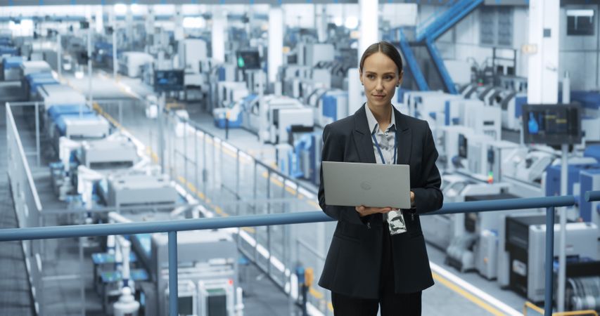 Electronics Manufacturing Technician Working on a Laptop Computer at a Factory Space. Female Specialist Developing, Maintaining, Upgrading Programs for Machine Production and Assembly