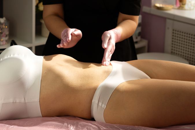 Spa therapist gently finishes abdominal massage using precise fingertip movements.