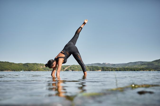 Side view of young woman practicing yoga while standing in shallow water