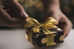 Man holding Christmas gift by wooden table