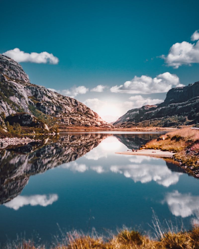 Mountains with reflection on lake under blue sky