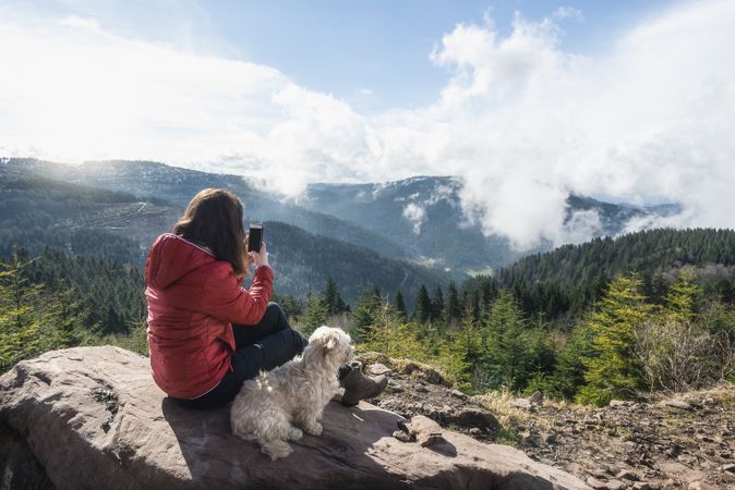 Woman hiker and dog pet on top of the forest