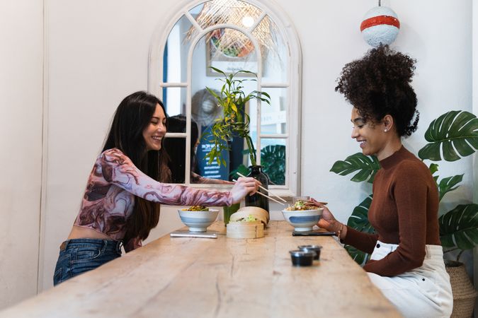 Delighted friendly multiethnic women eating in restaurant