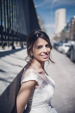 Smiling young fiancee near fence on street