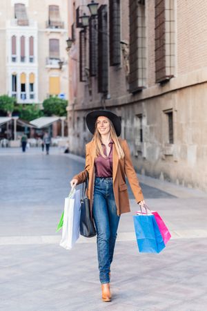Content female in trendy wear doing shopping at city street