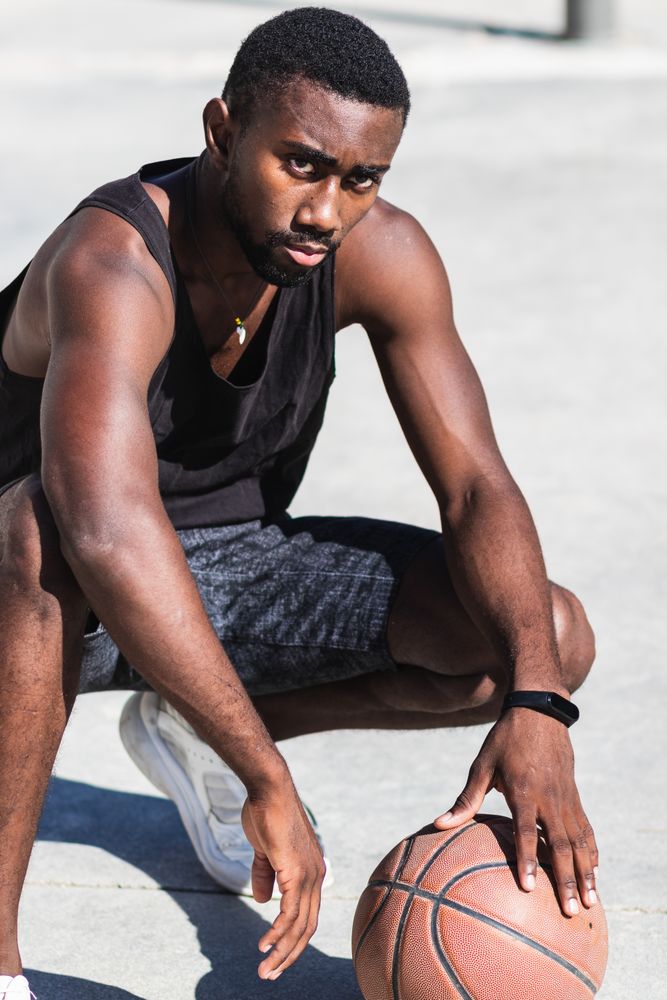 Confident Black sportsman on basketball court in summer