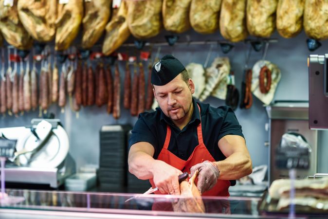 Butchers behind counter cutting ham