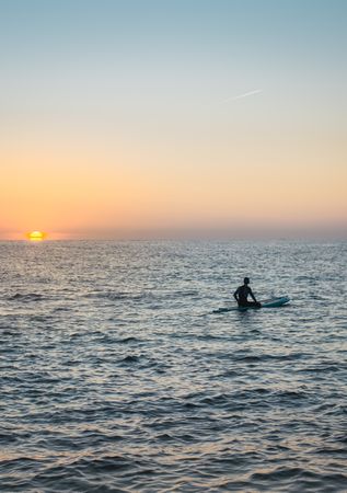 Man practicing paddle surfing with neoprene in a sunrise