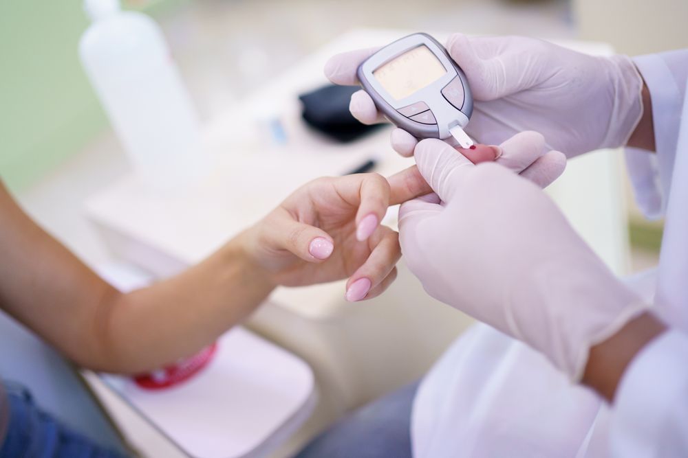 Doctor checking blood sugar level of patient's hand in hospital