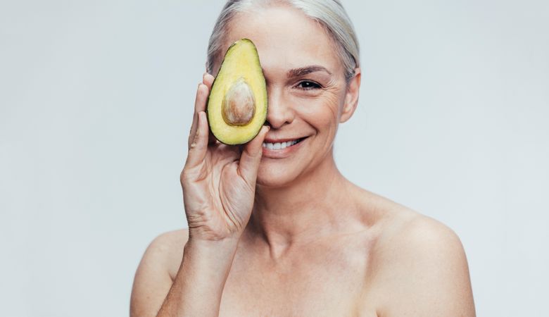 Female holding up avocado to camera