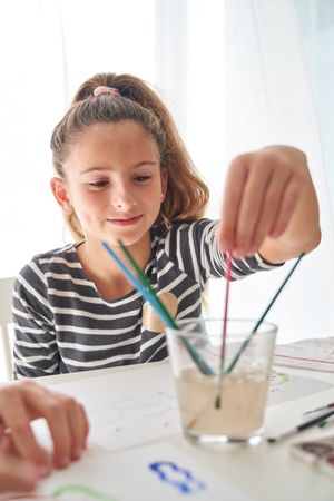 Content girl choosing paintbrush at table