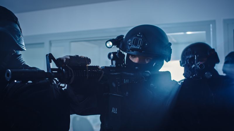 Close Up Portraits of Masked Squad of Armed SWAT Police Officers Storm a Dark Seized Office Building with Desks and Computers.