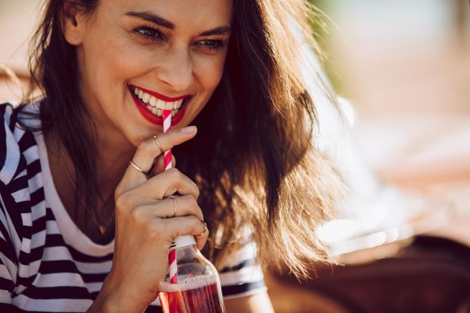 Close up of smiling female drinking soft drink on a summer day