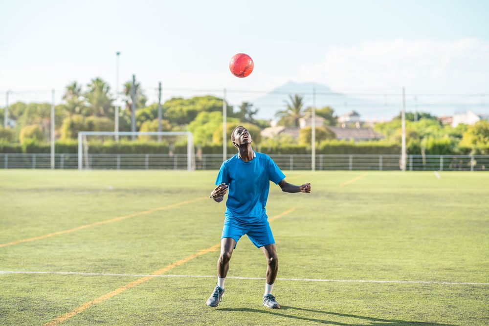 Black teenager jugging football ball on head