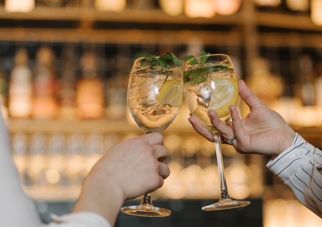 Close-up view of women hands toasting with cocktails in bar