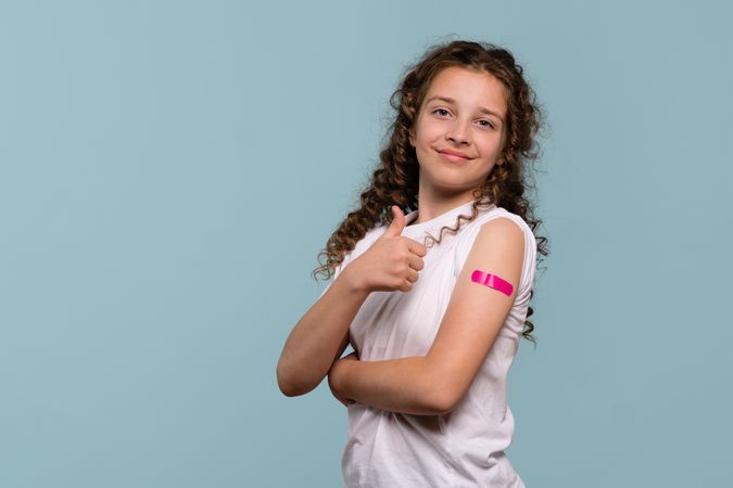 Girl giving thumbs up after vaccination.
